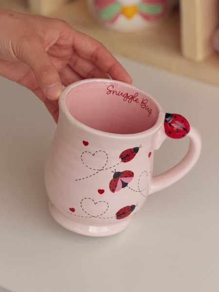 كوب برسومات ربيعية ودعسوقة على اليد وعبارة "SNUGGLE BUG" في الداخل